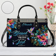 Hummingbird handbag on white table beside floral bouquet with texture swatch inset.