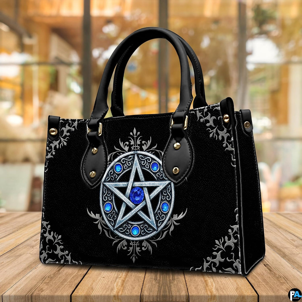 Silver pentagram handbag displayed on wooden tabletop in front of cafe window.