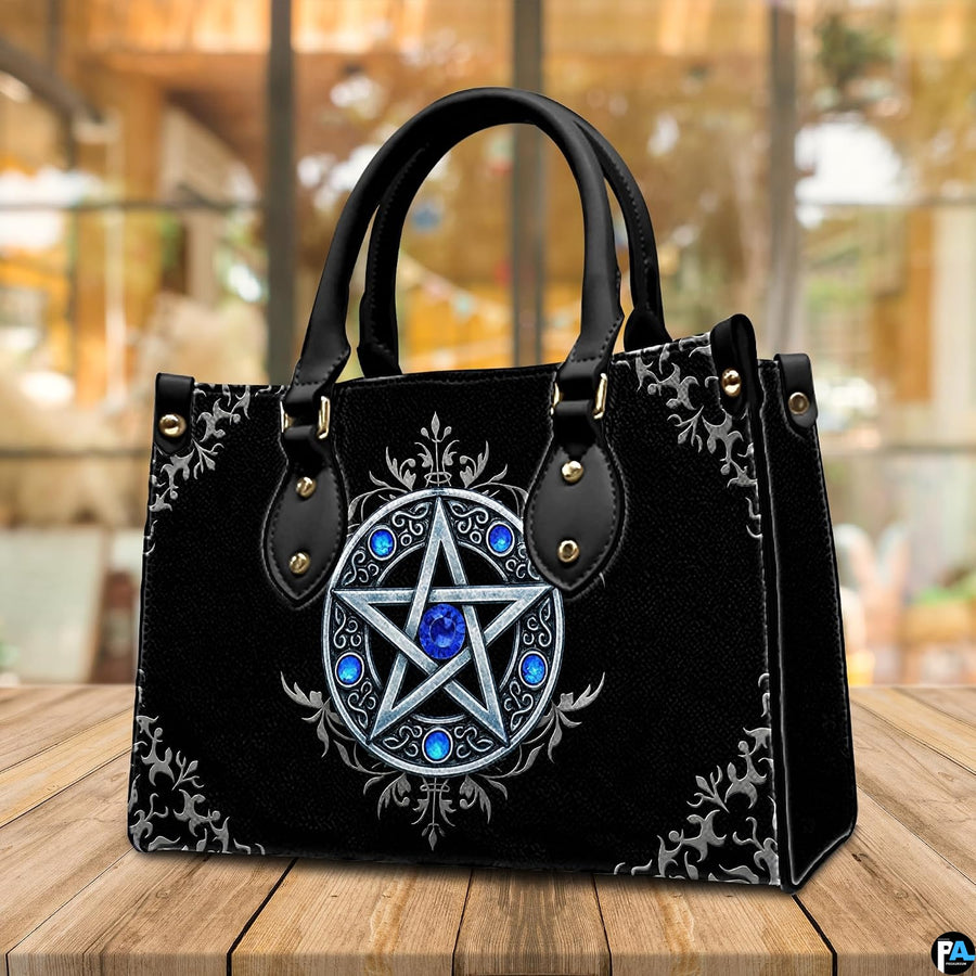 Silver pentagram handbag displayed on wooden tabletop in front of cafe window.