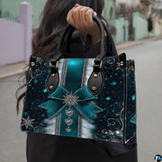 Lifestyle view showing handheld carry of teal snowflake handbag outdoors.