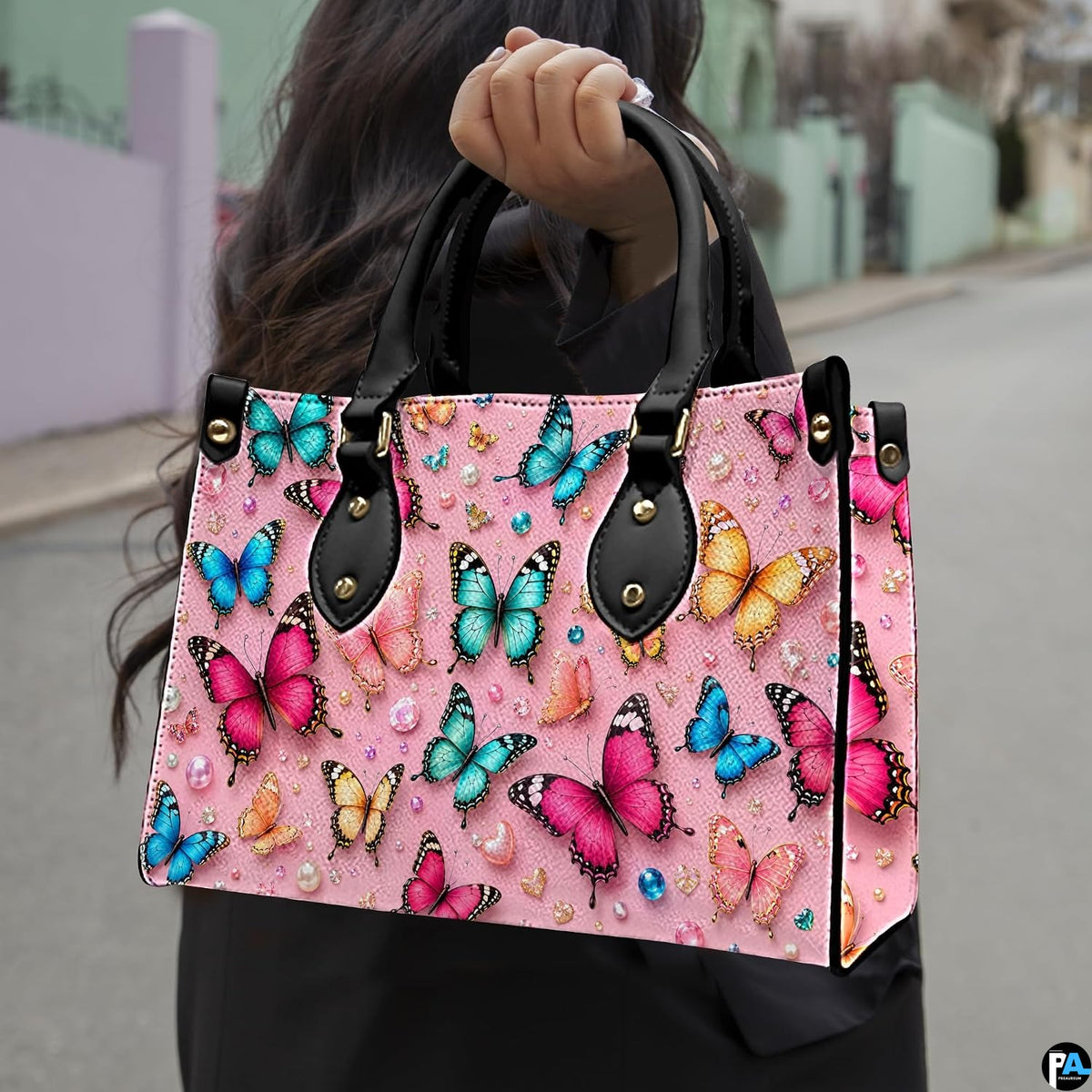 Outdoor street perspective showing colorful butterfly artwork held by pedestrian along town sidewalk.