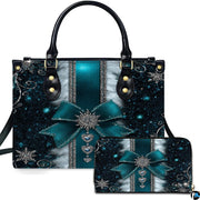 Front view of teal snowflake bow handbag and matching zippered wallet with silver holiday charms.