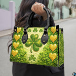 Model carrying gold heart clover handbag with glowing green artwork