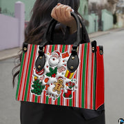 Model carrying the striped Christmas handbag with festive Santa graphics in an outdoor street setting.
