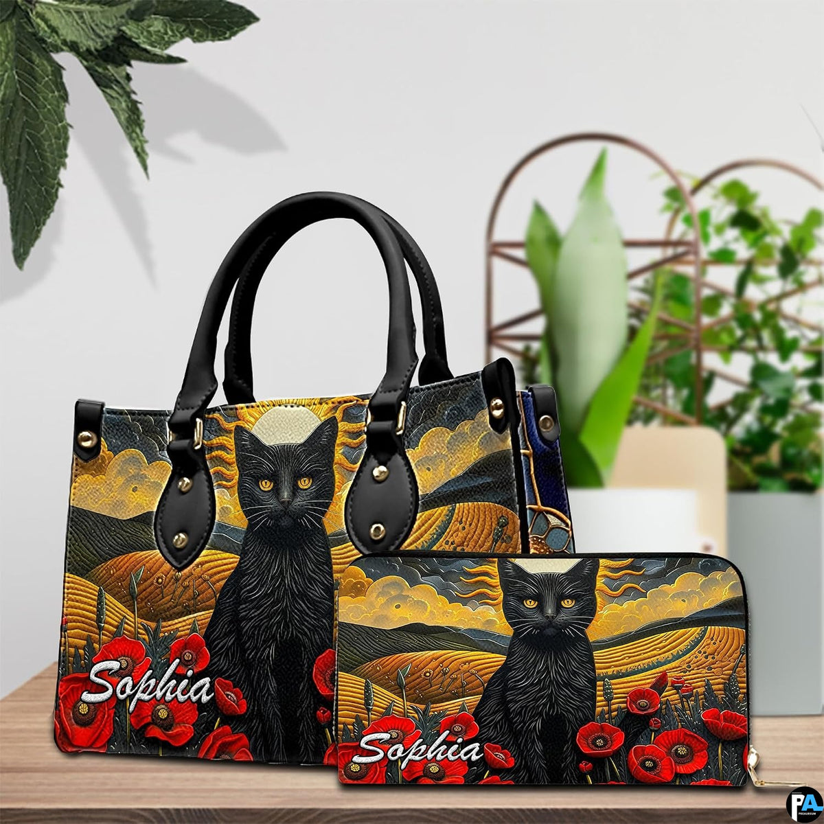 Tabletop presentation highlighting cat landscape art resting beside leafy indoor greenery.