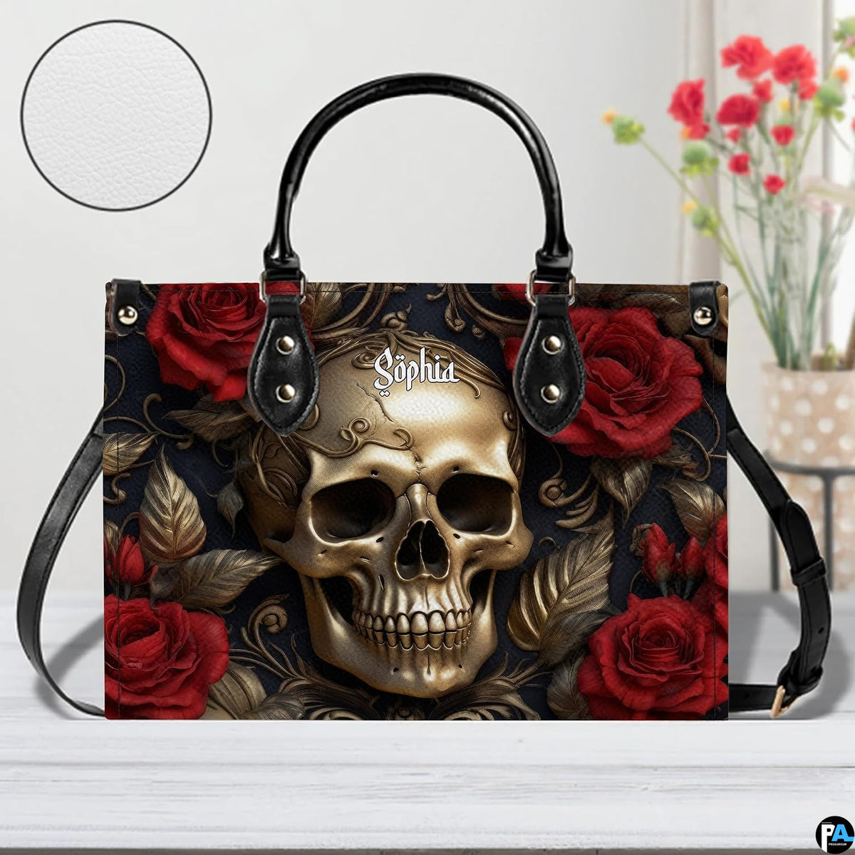 Golden skull handbag displayed on white table beside floral bouquet.