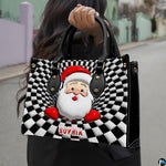 Lifestyle view showing handheld carry of optical illusion Santa handbag outdoors.