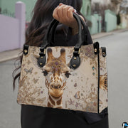 Front view of giraffe handbag displaying detailed portrait adorned with decorative forehead tiara.