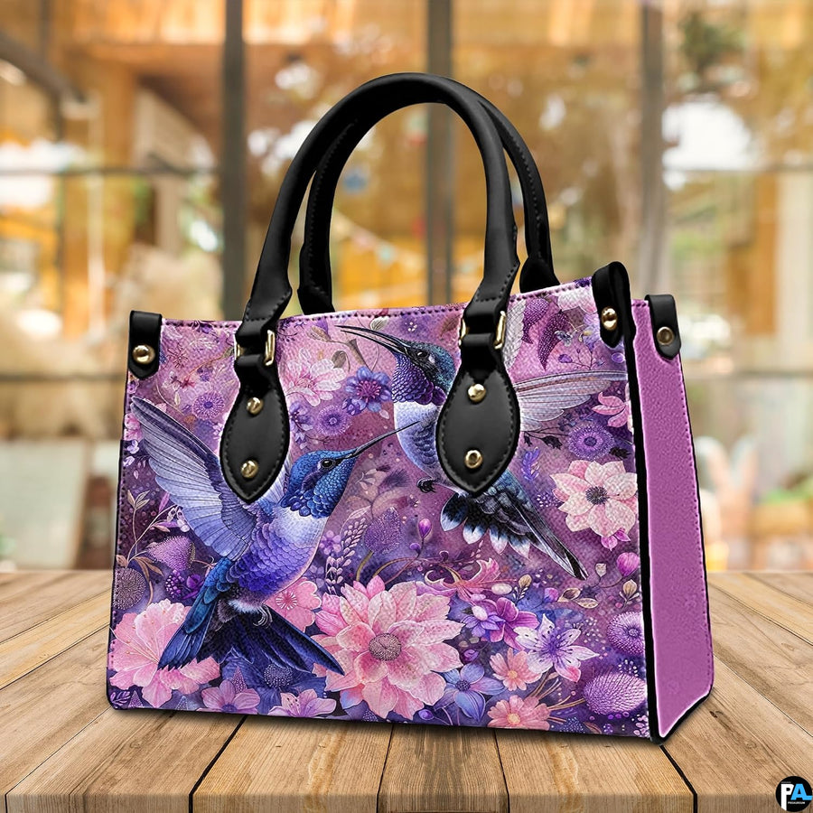 Back view of purple hummingbird handbag showing continuous botanical print coverage on white background.