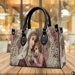 Lifestyle display showing handheld carry of the Madonna and Child handbag outdoors.