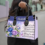 Floral cross handbag carried outdoors by top handle on residential street.