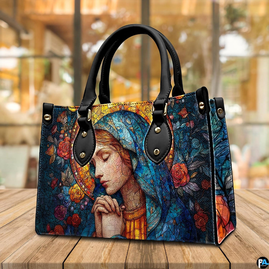 Three-quarter view of stained glass Mary handbag displayed on cafe table.