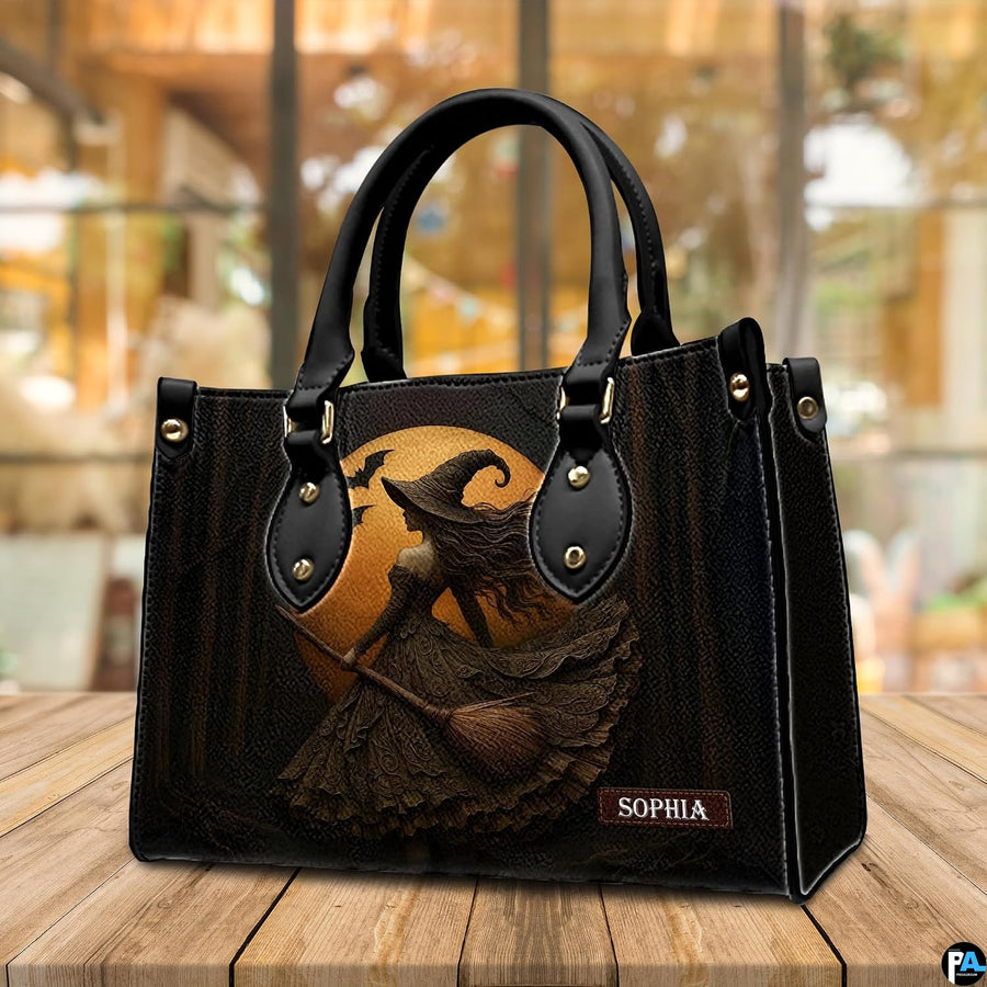 Gothic witch handbag displayed on wooden tabletop in front of sunlit window.