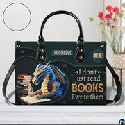 Author blue dragon handbag on white wooden table beside floral vase with texture swatch inset.