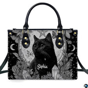 Gothic black cat handbag and matching wallet set on wooden table near houseplant.