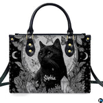 Gothic black cat handbag and matching wallet set on wooden table near houseplant.