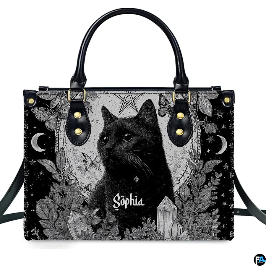 Gothic black cat handbag and matching wallet set on wooden table near houseplant.