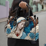 Model carrying the porcelain cameo Virgin Mary handbag over her shoulder on an outdoor walkway.