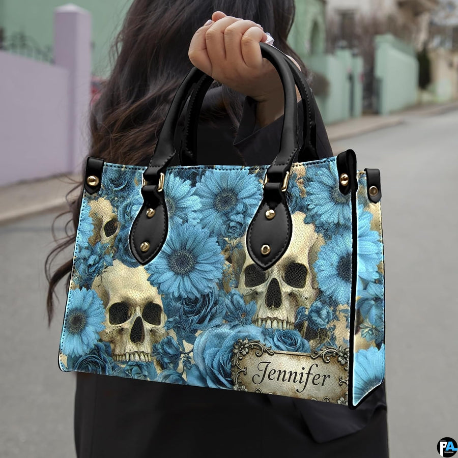 Skull floral daisy handbag carried outdoors by top handle along residential street.