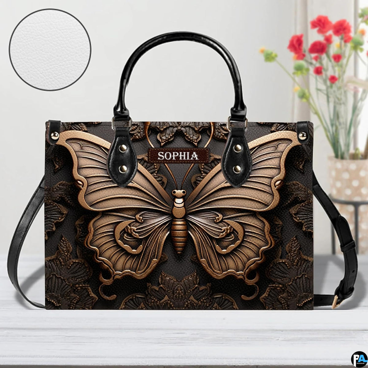 Artisan butterfly handbag displayed on a white surface alongside floral decor and a circular material swatch.
