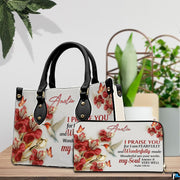 Hummingbird devotional handbag arranged with matching wallet on a tabletop beside decorative plant.
