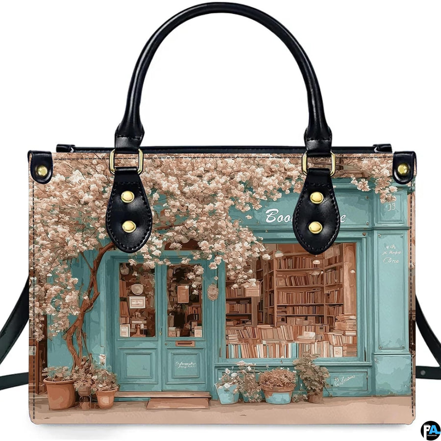 Front product view of vintage bookshop handbag displaying turquoise storefront art on pure white background.