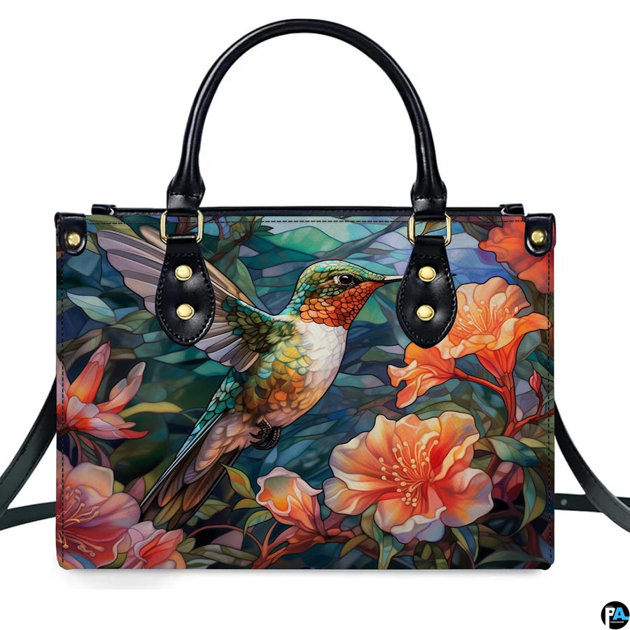 Studio front shot of mosaic hummingbird handbag showcasing outstretched wings and coral blossoms.