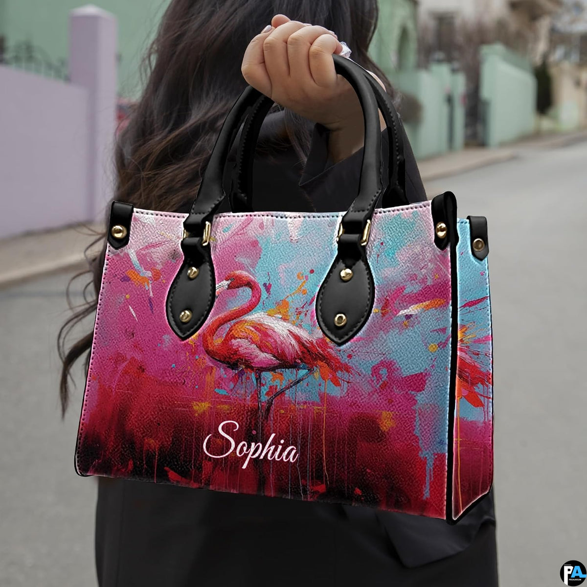 Outdoor lifestyle view of model carrying the paint splatter flamingo handbag on an urban street.