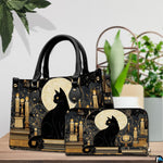 Black cat candles design resting beside potted greenery on a wooden surface.
