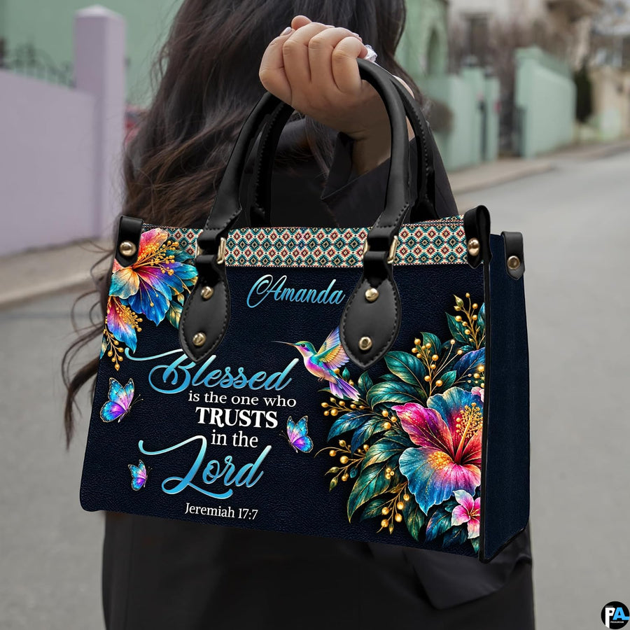 Hummingbird hibiscus handbag carried outdoors by top handle on residential street.