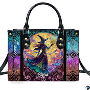 Stained glass witch handbag displayed on white table beside floral bouquet.
