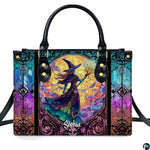 Stained glass witch handbag displayed on white table beside floral bouquet.