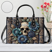 Front view of gothic floral skull grimoire handbag on table beside decorative floral vase.