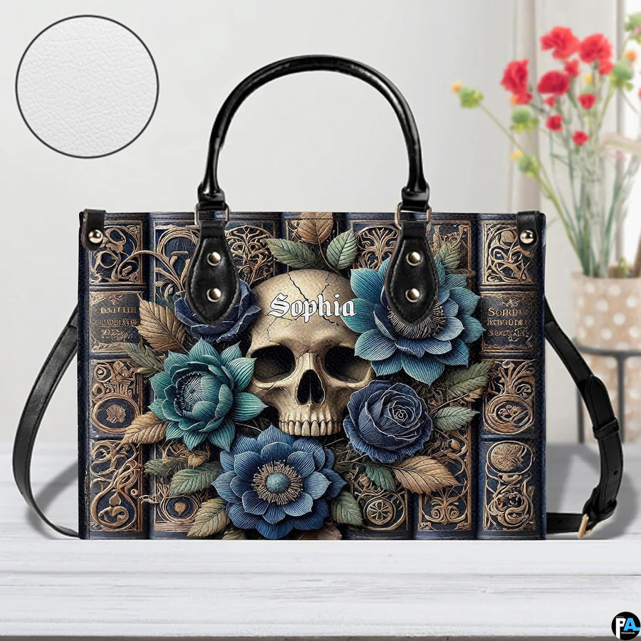 Front view of gothic floral skull grimoire handbag on table beside decorative floral vase.