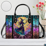 Stained glass witch handbag displayed on wooden tabletop in front of sunlit windows.