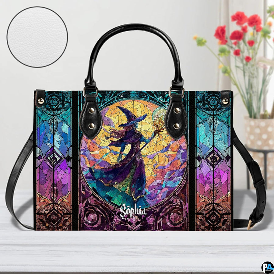 Stained glass witch handbag displayed on wooden tabletop in front of sunlit windows.