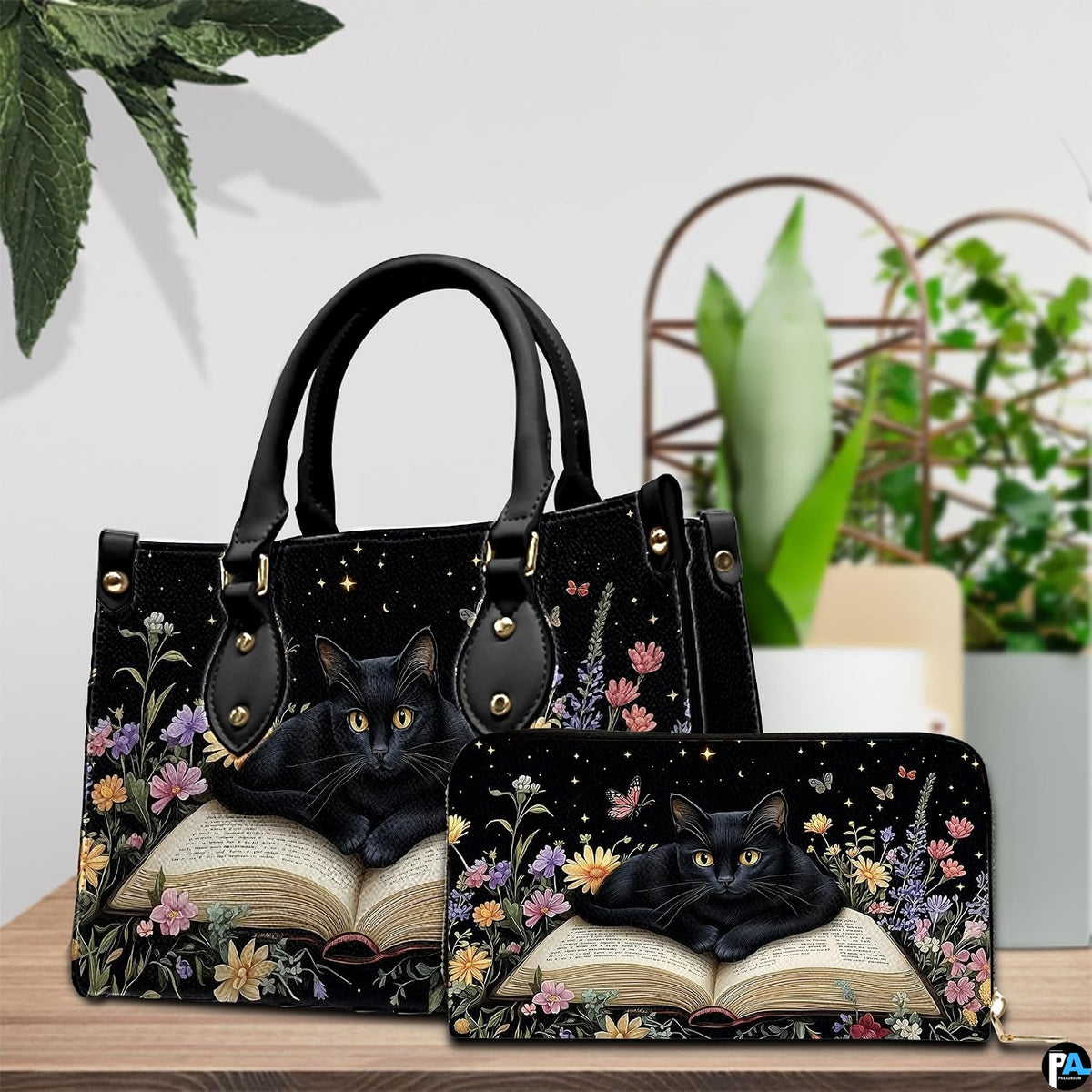 Indoor table view featuring bookish black cat artwork and companion accessory beside houseplants.