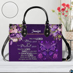 Christian blessing violet handbag displayed on white table beside floral bouquet.