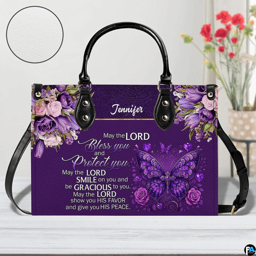 Christian blessing violet handbag displayed on white table beside floral bouquet.