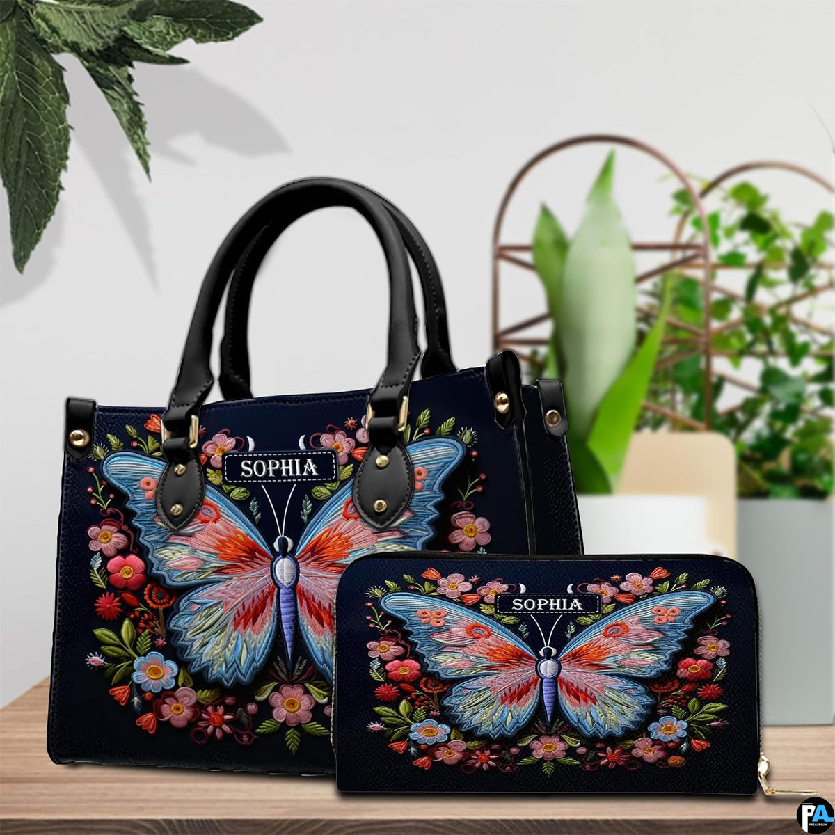 Top-handle handbag and matching wallet displayed together beside potted houseplants.