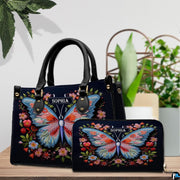 Top-handle handbag and matching wallet displayed together beside potted houseplants.