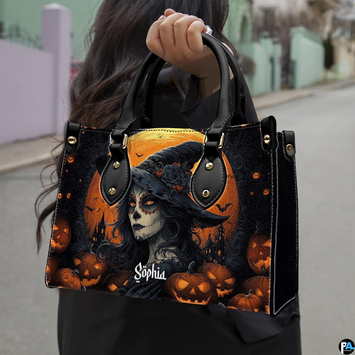 Sugar skull witch handbag held by top handle while walking outdoors along a residential street.