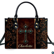Angled perspective view of western turquoise cross handbag displaying ornate scroll patterns.