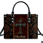 Angled perspective view of western turquoise cross handbag displaying ornate scroll patterns.