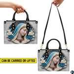 Cerulean cameo Virgin Mary handbag shown held by top handles and shoulder strap