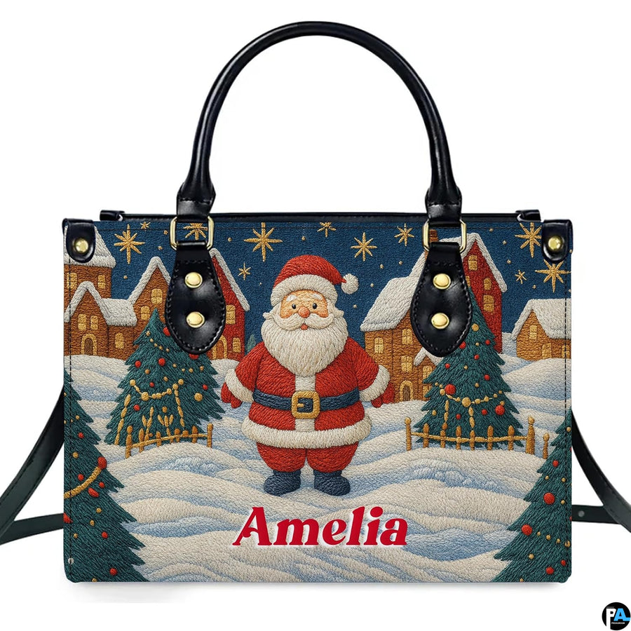 Front view of top-handle handbag featuring embroidered style Santa in a snowy Christmas village.