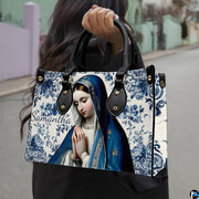 Outdoor street lifestyle display of blue ceramic tile praying Mary handbag.