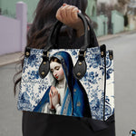 Outdoor street lifestyle display of blue ceramic tile praying Mary handbag.
