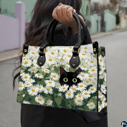 Street lifestyle setting of black cat in flower field painting held during a sunny stroll.