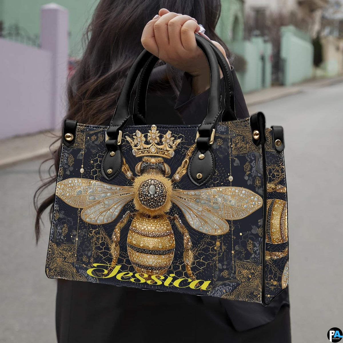 Side view of crowned queen bee handbag showing structured silhouette and black carrying handles.